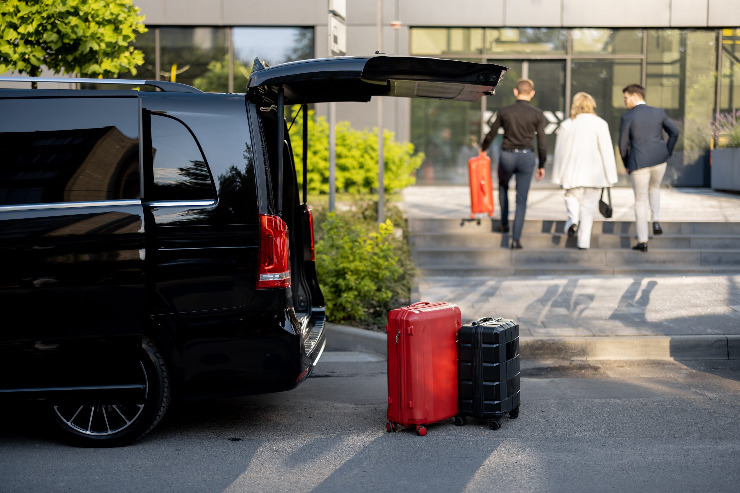 Driver or concierge helps a business couple carry their suitcases to the office or hotel from a minivan taxi. Concept of business travel and transportation service